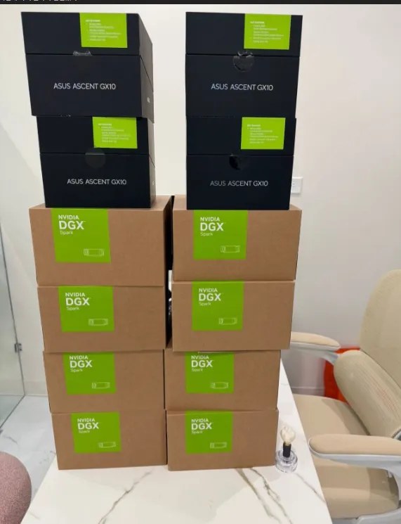 탁자 위에 NVIDIA DGX Spark 상자 8개와 ASUS Ascent GX10 상자 4개가 두 줄로 높이 쌓여 있는 사진