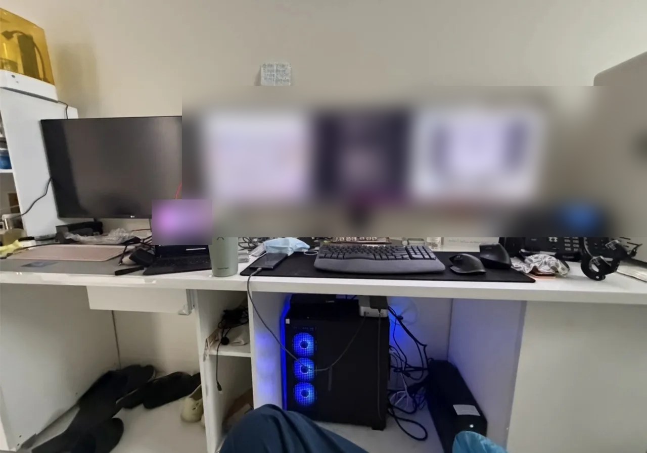 원장실 책상. 와이드 모니터에 병원 카메라 화면과 검은 명령줄 창이 떠 있고, 옆에 노트북과 사무실 전화기, 책상 아래에 파란 불빛의 컴퓨터 본체가 있다